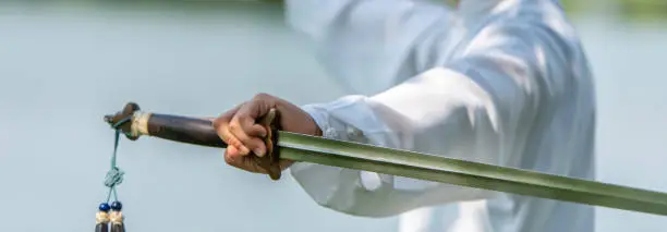 Photo of Asian man doing Tai Chi in the park.