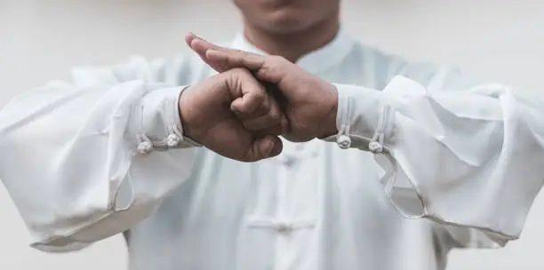 Photo of Asian man doing Tai Chi in the park.