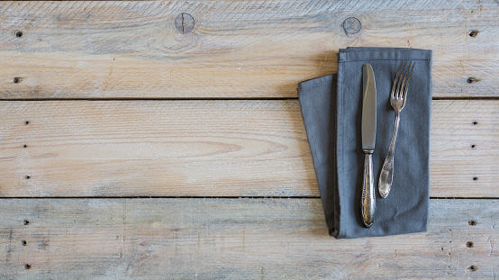 Cutlery and napkin on used look wooden background.