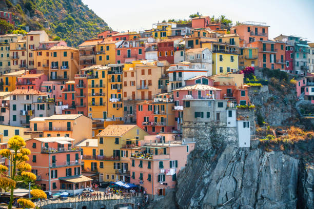 Pastel houses with balconies, green shutters, and hanging laundry line the hillside in Manarola, Cinque Terre, Italy, forming a dense mosaic of Mediterranean color