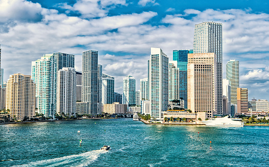 miami skyline. Yachts sail on sea water to city skyscrapers on cloudy blue sky in Miami, USA. Summer vacation, wanderlust, travelling, lifestyle concept.