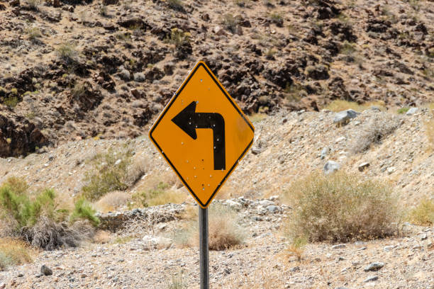 istock Yellow traffic sign Left Turn in the desert with bullet marks 1260384757