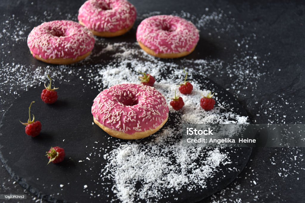Pink Donuts on a dark plate Pinky Donuts on a dark plate with a decoration of fresh raspberries and grated coconut. Donut stack oand Donut Tower - Top view and close up Backgrounds Stock Photo