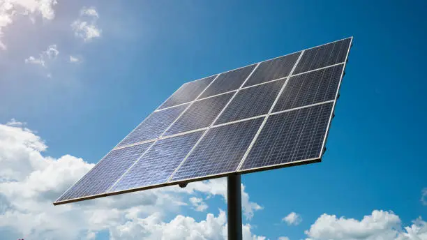 Clean green energy.  A large solar power panel at a solar farm with bright sun against blue sky.