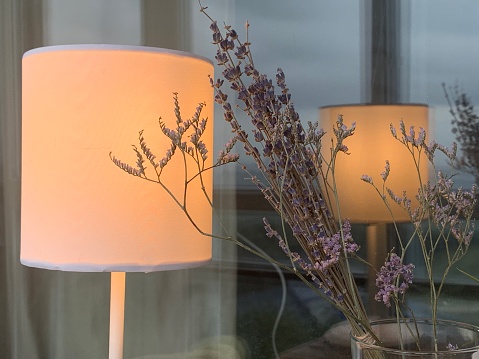 A table lamp turned on and dry lavender in a vase