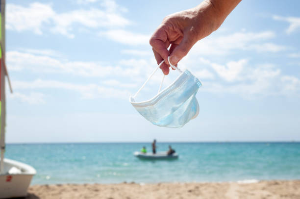 istock Woman holding a face mask on the beach 1260444134