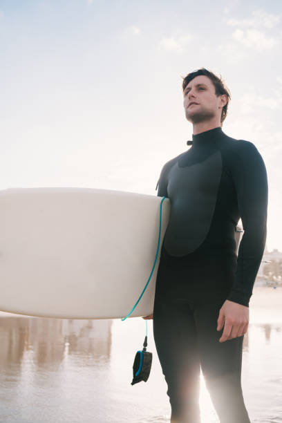 istock Surfer standing in the ocean with his surfboard. 1260446328
