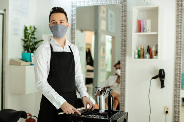istock Young hairdresser wearing protective face mask while working at hair studio during virus epidemic. 1260448471