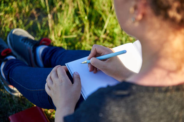 istock Woman writes with a pen in a clean notebook on the grass. 1260454339