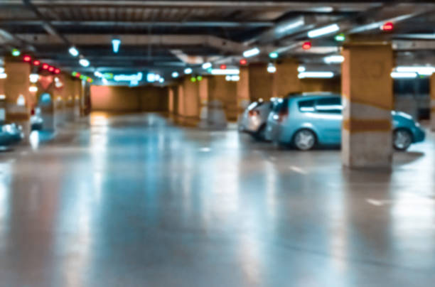 Garage interior blurred. Car lot parking space in underground city garage. Empty road asphalt background in soft focus. Large private garage. Garage interior blurred. Car lot parking space in underground city garage. Empty road asphalt background in soft focus. Large private garage empty dealership interior stock pictures, royalty-free photos & images