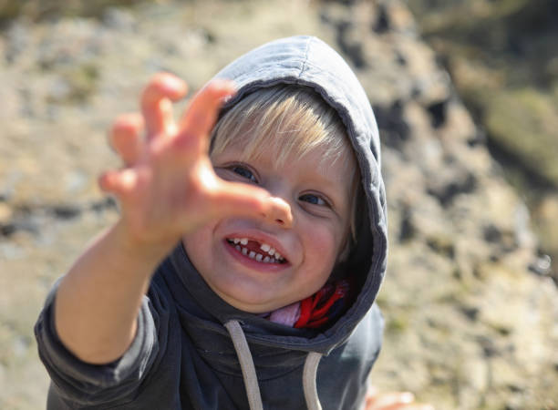 istock A young boy making a claw with his hand while smiling at the camera. 1260483412