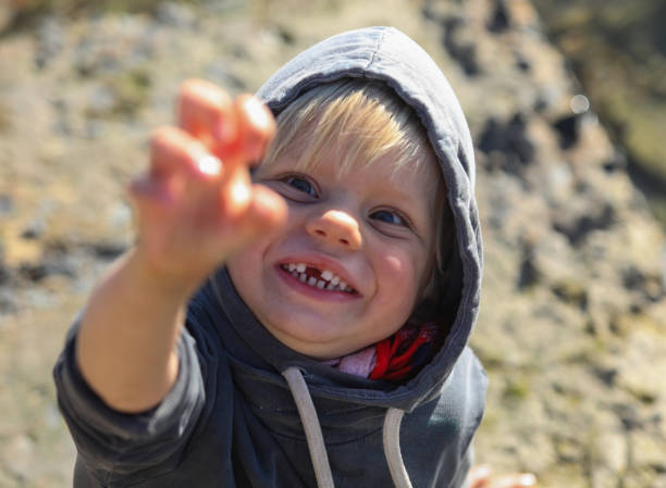 istock A young boy making a claw with his hand while smiling at the camera. 1260483439