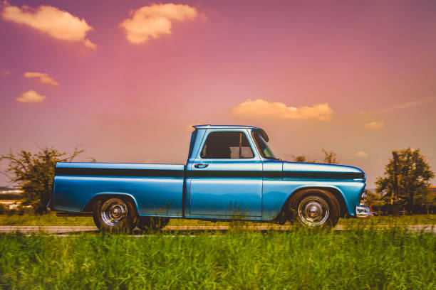 Side view of an old classic car on the street. Retro style photo of an american oldtimer pick-up from the 1960's. Vintage USA truck at sunset. Oldschool travel, traffic concept - fotografia de stock