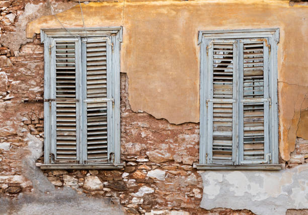 Two old wooden windows with shutters, on grunge weathered wall.