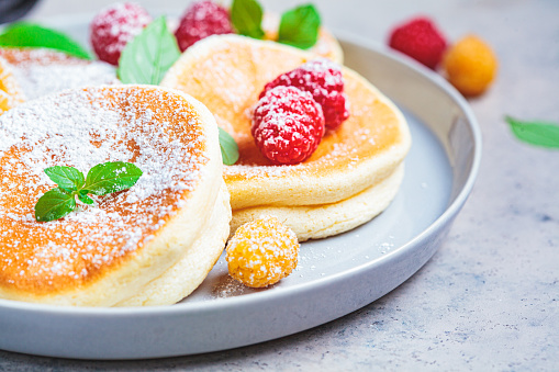 Japanese fluffy pancakes with raspberries in a gray plate, gray background. Japanese cuisine concept.
