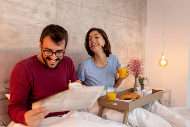 istock Couple reading newspapers and having breakfast in bed 1260539052