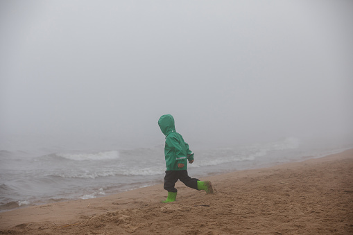 Baby walks in the fog on the shore of the lake