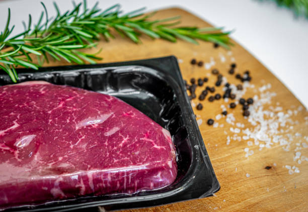 Beef steak in vacuum skin packaging and spices on wooden chopping board stock photo