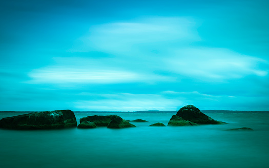 Tranquil landscape of the rocky beach. Long exposure photography at dusk on Cape Cod, Massachusetts, USA.