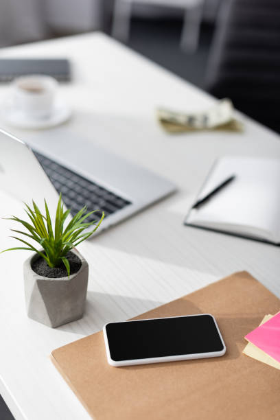 istock Selective focus of smartphone with blank screen near laptop and notebook on table, earning online concept 1260568292