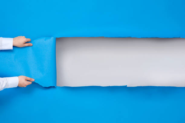 istock Man's hands tears up blue paper background with white copy space for your text. 1260603081