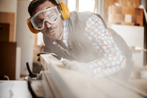 istock Young carpenter blowing off sawdust while cutting plank on a sawing machine 1260635639