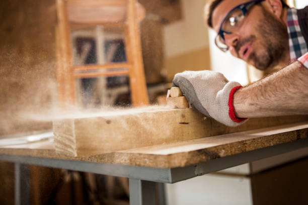 istock Young carpenter blowing off sawdust while using Sand paper on a plank of wood 1260635675