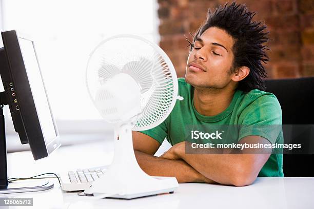 Young Man In Office With Blowing Electric Fan Stock Photo - Download Image Now - Electric Fan, Office, Heat - Temperature