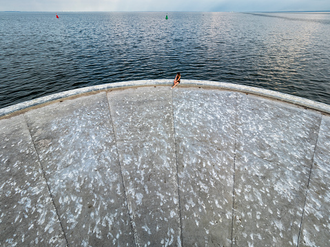 A woman sitting on a concrete breakwater at Szczecin Lagoon (Stettin Lagoon, Bay of Szczecin, Stettin Bay or Oder lagoon) - a lagoon in the Oder estuary, shared by Germany and Poland. It is separated from the Pomeranian Bay of the Baltic Sea by the islands of Usedom and Wolin. Image taken from a beacon.