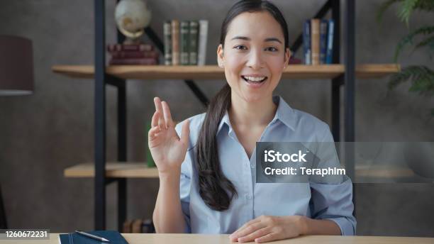 Smiling Young Asian Woman Teacher Conducts Online Lesson Looking At Camera Stock Photo - Download Image Now