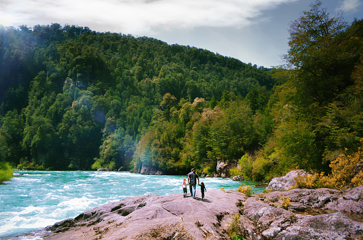Man with two children hiking along the Rio Futaleufu river in the Patagonia wilderness of Chile, South America