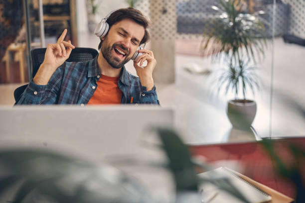 istock Cheerful young man listening to music at work 1260696132