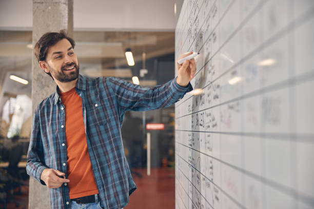 istock Joyful young man writing on whiteboard in office 1260700265