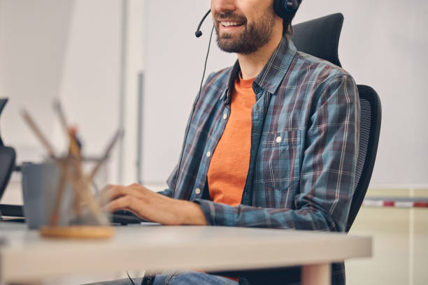 istock Joyful call center worker sitting at the table in office 1260700284