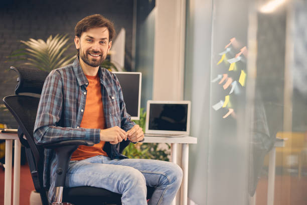 istock Joyful young man sitting in chair at work 1260700329