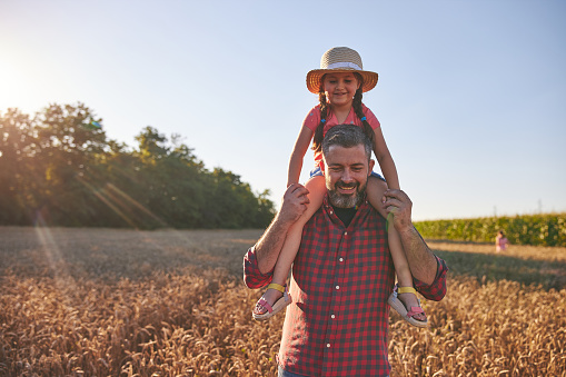Beautiful and cheerful father and daughter enjoying the time together in a wheat field.