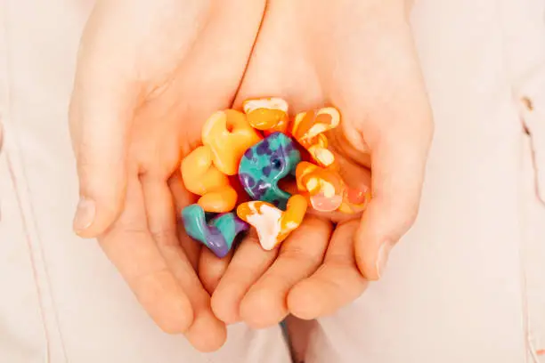 Photo of Different types of ear plugs in female hands, top view. Personally molded earplugs for noisy places, different colors and very stylish