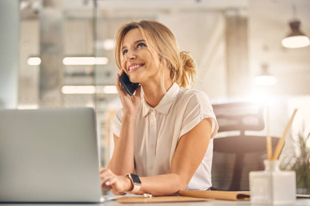 istock Cheerful young woman having phone conversation at work 1260734109