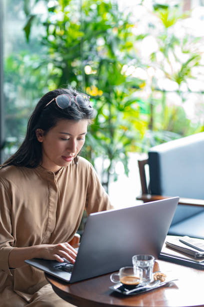 istock Asian Woman/ College Student Using a Laptop Computer to Study Remotely at a Cafe 1260743472