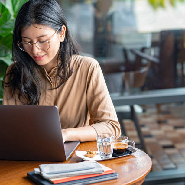 istock Asian Woman/ College Student Using a Laptop Computer to Study Remotely at a Cafe 1260743474
