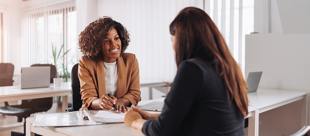 Mujer consultando con una gerente financiera femenina en el banco photo