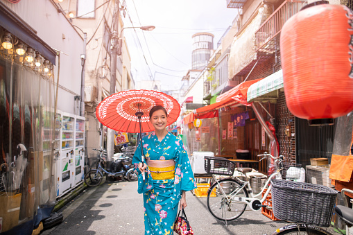 Young woman in yukata walking in traditional Izakaya bar street for sightseeing