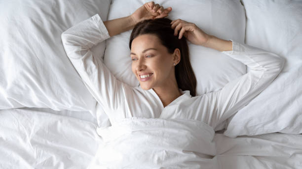 istock Millennial woman in white pyjama lying in bed feels rested 1260812535