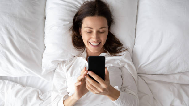 istock Top view woman lying in bed use cellphone check messages 1260812539
