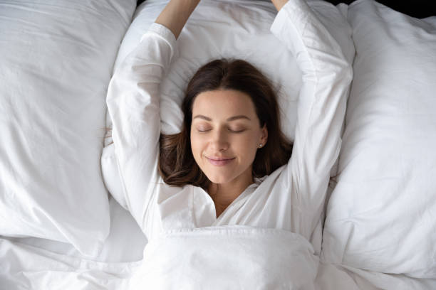 istock Woman stretching hands waking up after night sleep top view 1260812546
