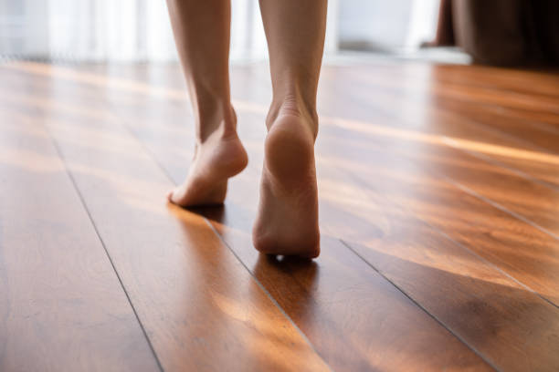 Woman walking barefoot on toes at warm floor closeup view Woman walking barefoot on toes at warm laminate floor close up rear view. Sunny light bedroom good morning welcome new day, modern comfy apartments with under floor heating system, footcare concept hardwood floor stock pictures, royalty-free photos & images