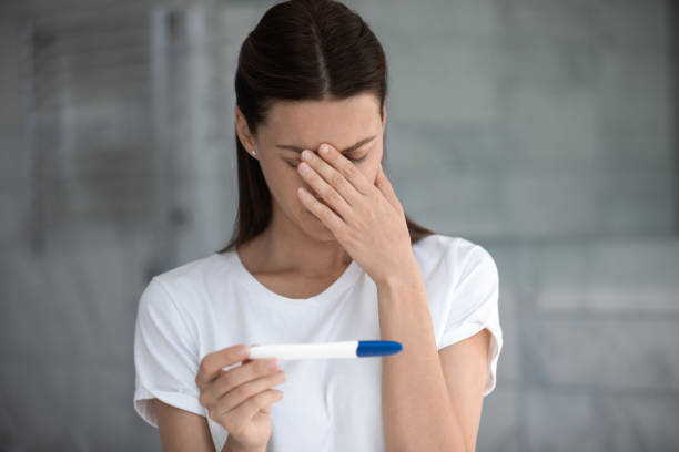Upset woman looking at pregnancy test bad result feels disappointed Stressed millennial woman holding pregnancy test feeling disappointed by negative result female health problems and infertility. Concept of two stripes and unwilling pregnancy, decision about abortion unwanted pregnancy stock pictures, royalty-free photos & images
