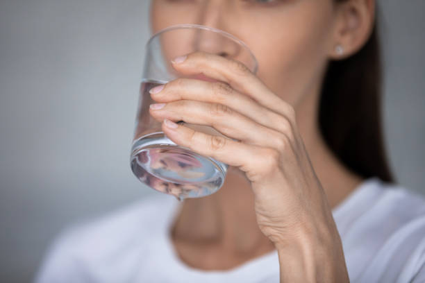 istock Closeup focus on female hand holding glass drinking still water 1260813112