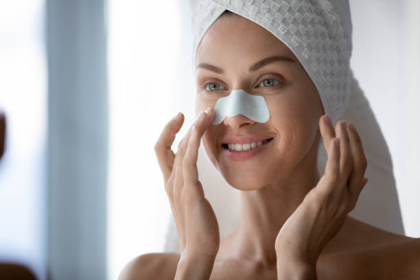 Woman using cleansing nose strips deep purifying treatment removing blackheads