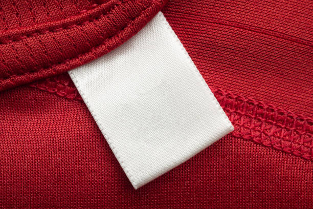 赤いポリエステルスポーツシャツの背景に白い空白のランドリーケア服のラベル - ラベル 写真 ストックフォトと画像
